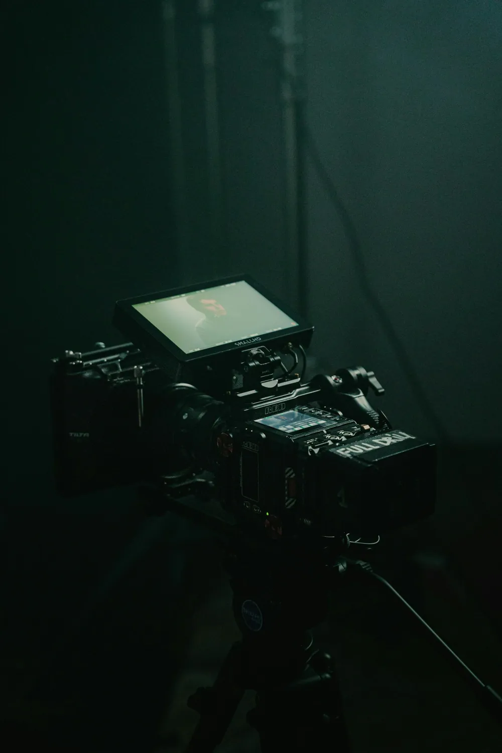 Cinema camera set up in a dark studio, monitor glowing (Photo by Oleg Brovchenko on Unsplash)